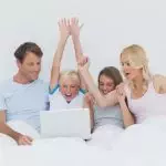 Family using a laptop in bed